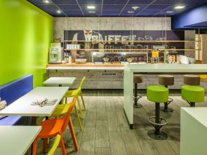 um restaurante com paredes verdes, mesas e cadeiras em ibis budget Duesseldorf Willich em Willich