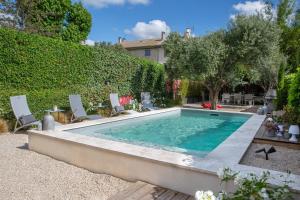 a swimming pool in a yard with chairs and trees at L’annexe in Orange
