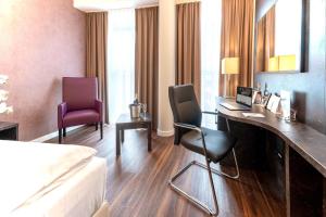 um quarto de hotel com uma cama, uma secretária e cadeiras em Best Western Plus Plaza Berlin Kurfürstendamm em Berlim