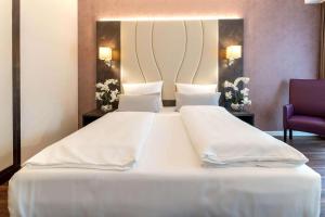 Cama blanca grande en habitación con silla morada en Best Western Plus Plaza Berlin Kurfürstendamm en Berlín