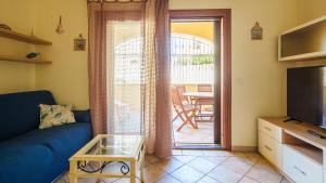 sala de estar con sofá azul y puerta corredera de cristal en Welcomely - La Porta Sul Mare en Golfo Aranci