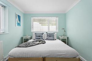 een slaapkamer met een bed met blauwe muren en een raam bij The Retreat, Brixham in Brixham