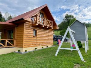 a log cabin with a balcony and a swing at Borówkowy Jar in Ropienka