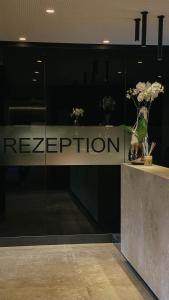 a reception desk with a vase of flowers on it at Klein Fein Hotel Anderlahn in Parcines