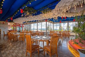 een restaurant met tafels, stoelen en ramen bij DONG PHUONG HOTEL in Bao Loc