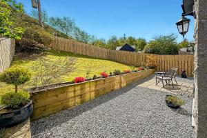 a garden with a wooden fence and a table and chairs at Skyfall Glencoe at Creag an-t Sionnaich in Glencoe