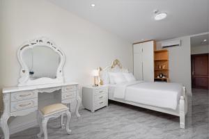 a bedroom with a white bed and a vanity and a mirror at DONG PHUONG HOTEL in Bao Loc