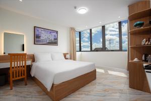 a bedroom with a bed and a desk and windows at DONG PHUONG HOTEL in Bao Loc