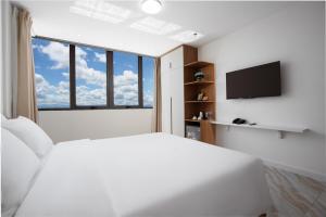 a white bedroom with a large bed and a tv at DONG PHUONG HOTEL in Bao Loc