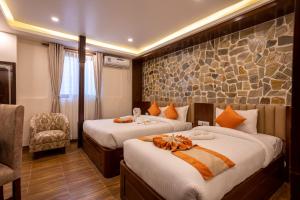 a hotel room with two beds and a chair at Airport Himalaya Boutique Hotel in Kathmandu