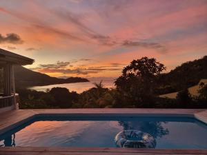 a swimming pool with a sunset in the background at Mirella Villa Holiday Apartment in Praslin
