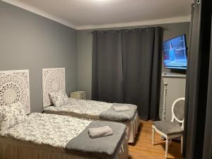 a bedroom with two beds and a flat screen tv at Skrunda Apartments Elvira in Skrunda