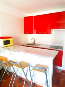 une cuisine avec des placards rouges et un comptoir avec des tabourets dans l'établissement Mareverde, wifi free, à Adeje