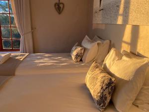 uma cama com lençóis brancos e almofadas num quarto em Tierkloof Mountain Cottages em Breede River DC