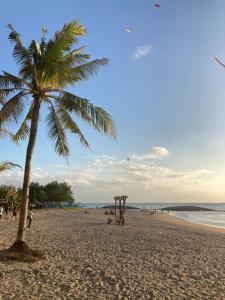 a palm tree on a beach with people on it at Rumahku Bali Executive in Kuta