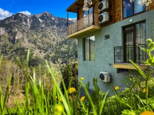 a house with a balcony and mountains in the background at Hotel Khulo lnn in Khulo