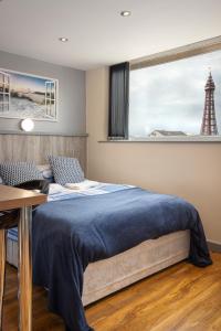 1 dormitorio con cama, escritorio y ventana en Seaside Suites Superior Family Apartments, en Blackpool