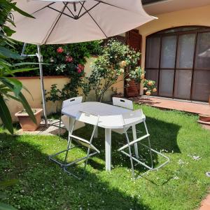 a white table and an umbrella in the grass at la casa di sandra in Pugnano