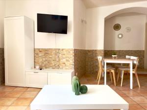 a living room with a table and a tv on the wall at Dimora Saracena Forio in Forio d'Ischia