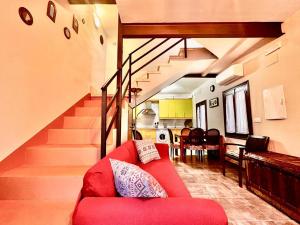 ein Wohnzimmer mit einem roten Sofa und einer Treppe in der Unterkunft CR "Calle Real" en la Sierra de Gredos in Villanueva de la Vera