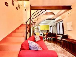 a living room with a red couch and a staircase at Casa Rural "Calle Real" en La Vera in Villanueva de la Vera
