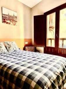 ein Schlafzimmer mit einem Bett mit einer blau-weißen karierten Decke in der Unterkunft CR "Calle Real" en la Sierra de Gredos in Villanueva de la Vera