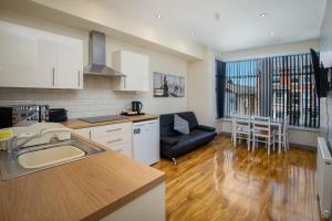 a kitchen with a sink and a living room at Seaside Suites Superior Family Apartments in Blackpool