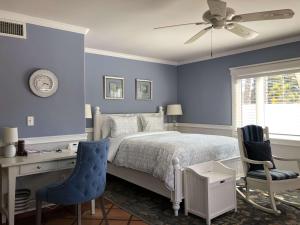 a bedroom with blue walls and a bed with a desk and chairs at Kate Stanton Inn in Encinitas