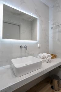 a white bathroom with a sink and a mirror at Vallia's Seaview Complex in Argassi