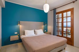 een slaapkamer met een groot bed met een blauwe muur bij Vallia's Seaview Complex in Argassi