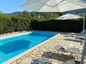 a swimming pool with an umbrella and two chairs at Metropolis Villa in Vathi