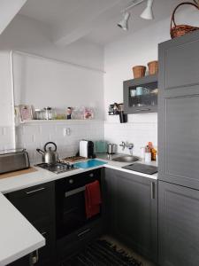 a kitchen with black cabinets and a sink at Ridii mieszkanie wakacyjne 800m od plaży - Brzeźno - AZW Gdańsk in Gdańsk