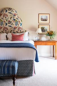 a bedroom with a bed with a headboard and a table at Ballymaloe House Hotel in Ballycotton