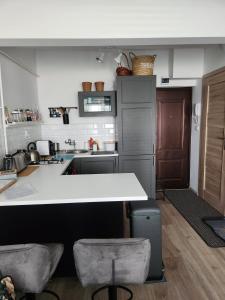 una cucina con bancone e 2 sgabelli da bar di Ridii mieszkanie wakacyjne 800m od plaży - Brzeźno - AZW Gdańsk a Danzica