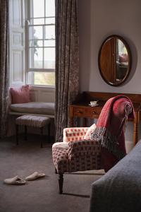 a living room with a chair and a mirror at Ballymaloe House Hotel in Ballycotton