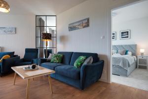 a living room with a blue couch and a bed at Apartamenty Pinea in Pobierowo