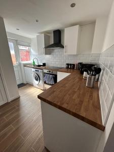 a kitchen with white cabinets and a wooden counter top at Charming Liverpool Home in Liverpool