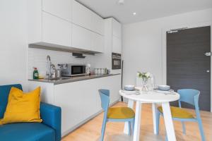 kuchnia i jadalnia z białym stołem i krzesłami w obiekcie Livestay-Modern Apartments Next To Wembley Stadium w Londynie