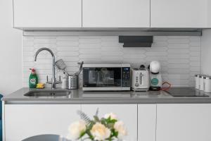 a kitchen counter with a microwave and a sink at Livestay-Modern Apartments Next To Wembley Stadium in London