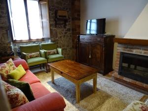 uma sala de estar com sofás, uma mesa e uma lareira em El Colladín em Llerices