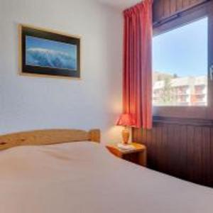 - une chambre avec un lit blanc et une fenêtre dans l'établissement Vacancéole - Résidence Plein Sud, à Les Deux Alpes