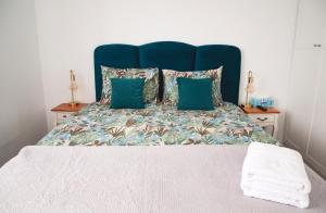 ein großes Bett mit blauem Kopfteil und grünen Kissen in der Unterkunft Elis Apart in Oradea