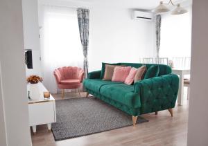 ein grünes Sofa mit rosa Kissen im Wohnzimmer in der Unterkunft Elis Apart in Oradea