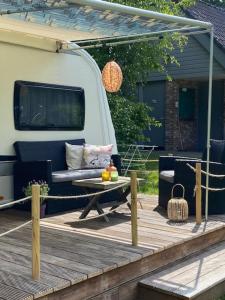 a patio with a couch and a table on a trailer at Caravan op Camping t Kopske in Den Hout in Den Hout