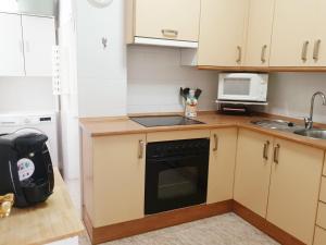 een keuken met witte kasten en een zwarte vaatwasser bij Soleado apartamento en Nerja in Nerja
