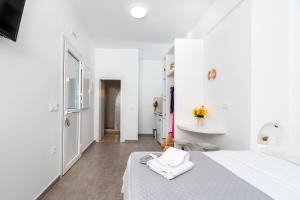 a white room with a bed and a mirror at Thallos Cave House and Apartments in Karterados
