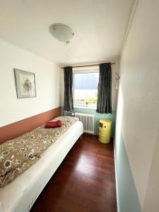 a small bedroom with a bed and a window at Cosy apartment near beach, marina & city centre in Tórshavn