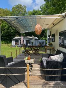 een patio met banken, een tafel en een tent bij Caravan op Camping t Kopske in Den Hout in Den Hout