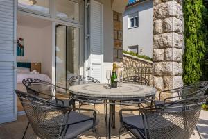 - une terrasse avec une table et des chaises ainsi qu'une bouteille de vin dans l'établissement Villa Veronika Apartments, à Crikvenica