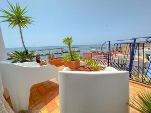 a balcony with white chairs and a view of the beach at La casa del pescatore in Sciacca